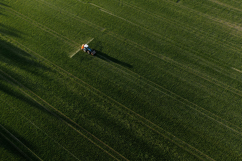 Aerial view of tractor spraying pesticides at agriculture field